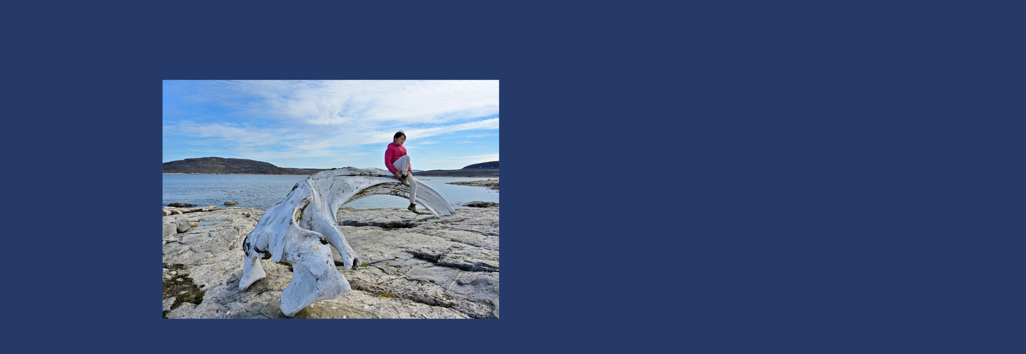 An Inuk young person perched on a whale bone along the Arctic shore of Baffin Island