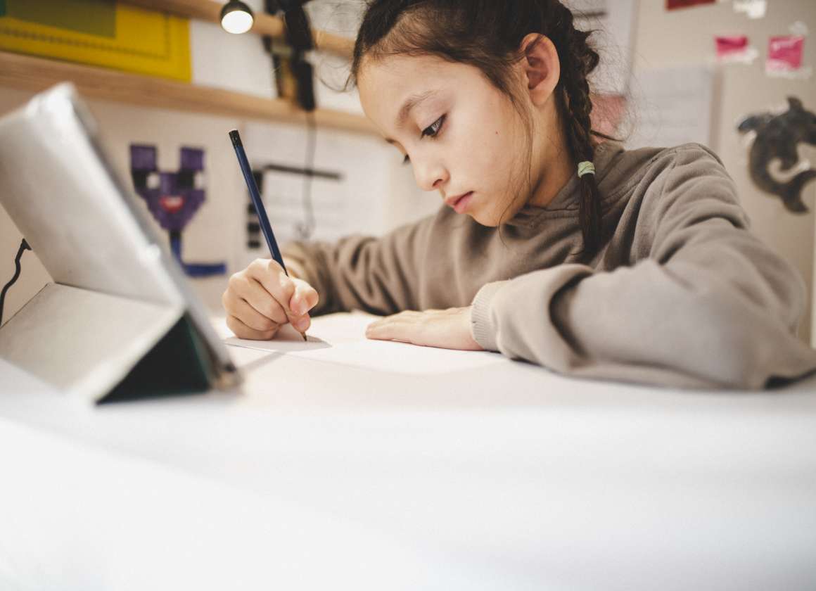An image on a web page about Kids Help Phone’s mental health website of a young person drawing at a desk looking at a tablet