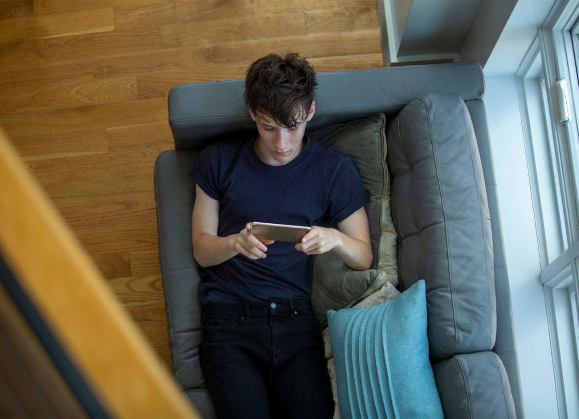 An image on a web page about Kids Help Phone’s mental health website of a young person on a couch looking at a phone
