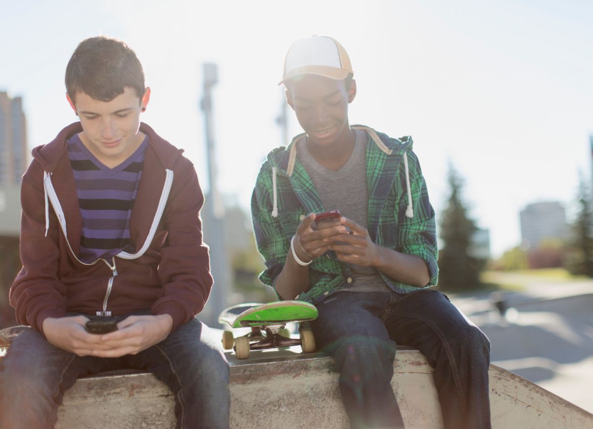 An image on a web page about Kids Help Phone’s mental health website of two young people sitting outside and texting