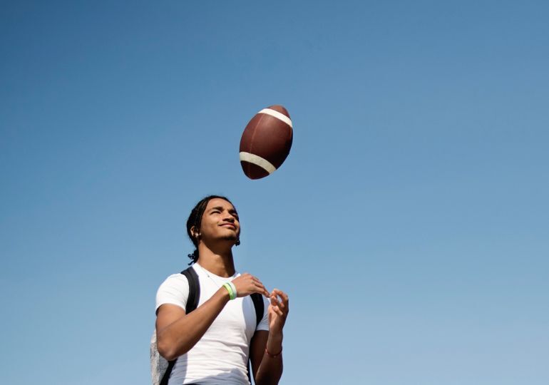 Young person tossing a football in the air