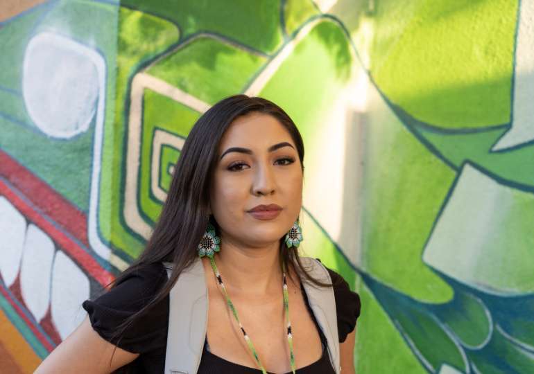Indigenous person standing in front of colourful wall
