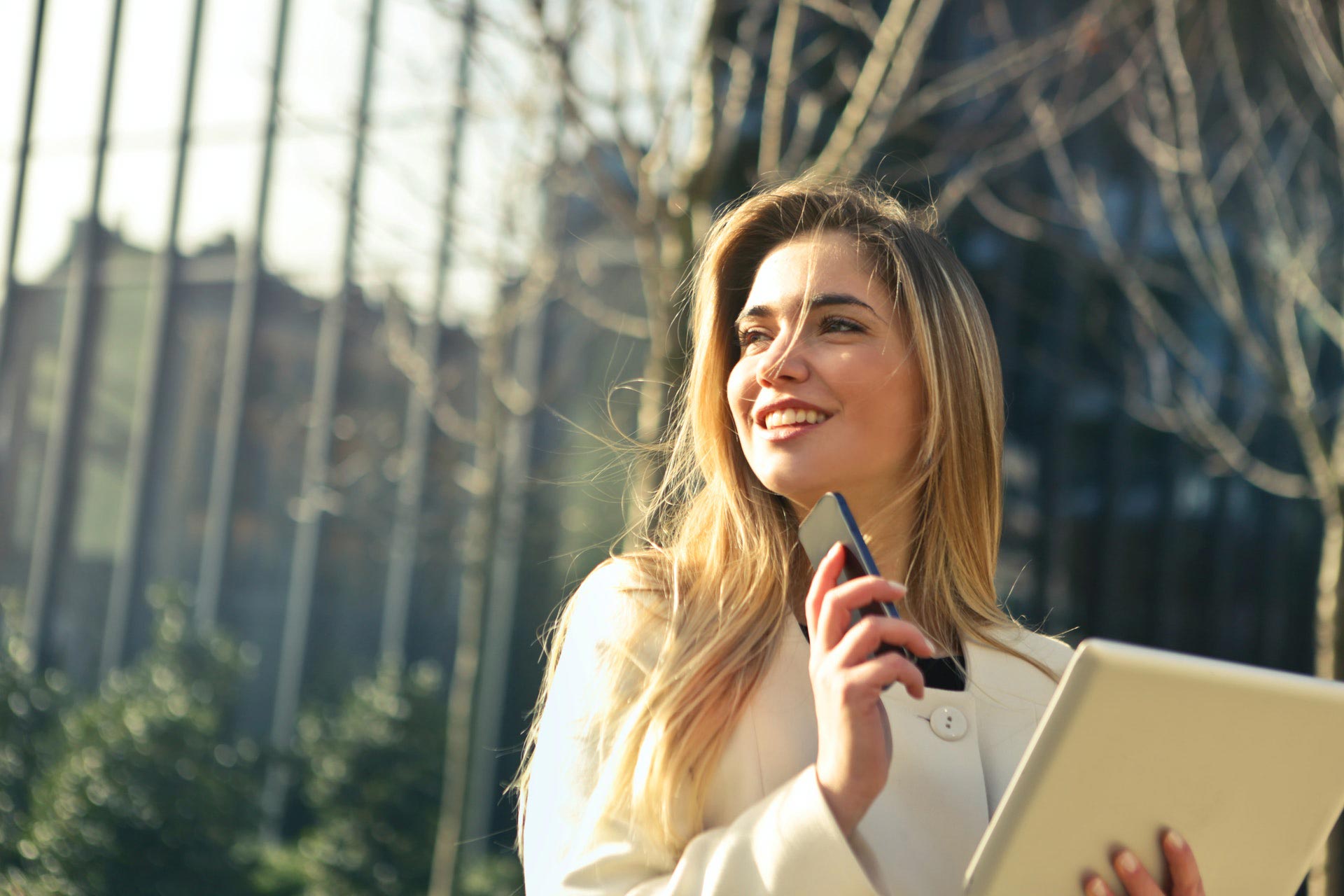 woman wearing white top holding a phone