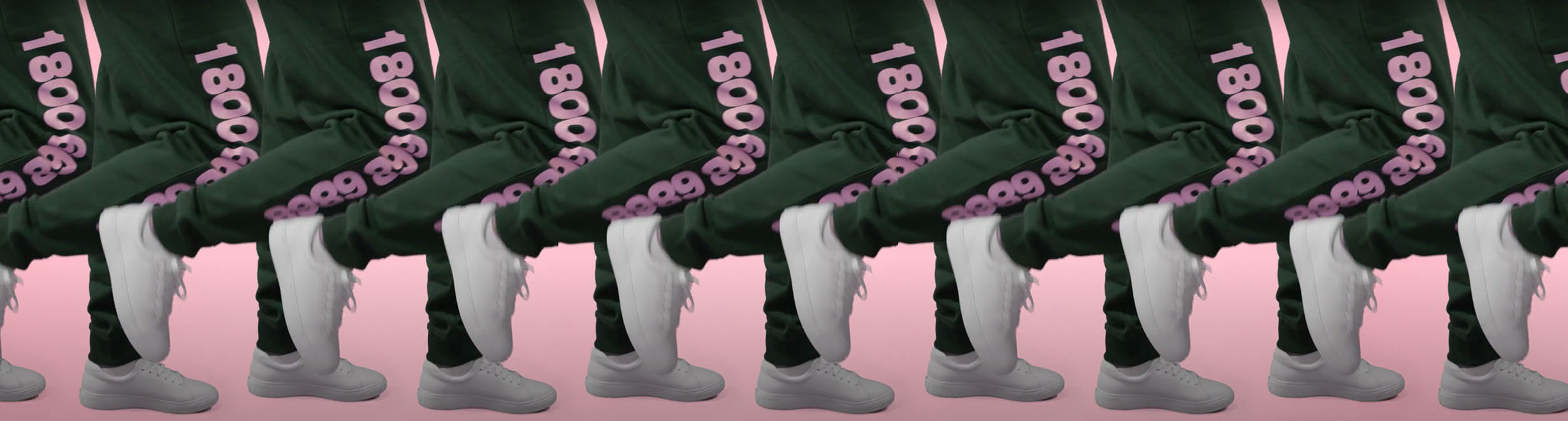 Image of a person's legs, wearing green sweatpants with pink printing on the side